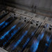 American Made Grills Encore 54-Inch Hybrid Grill close-up of stainless steel heat zone separators with blue flame