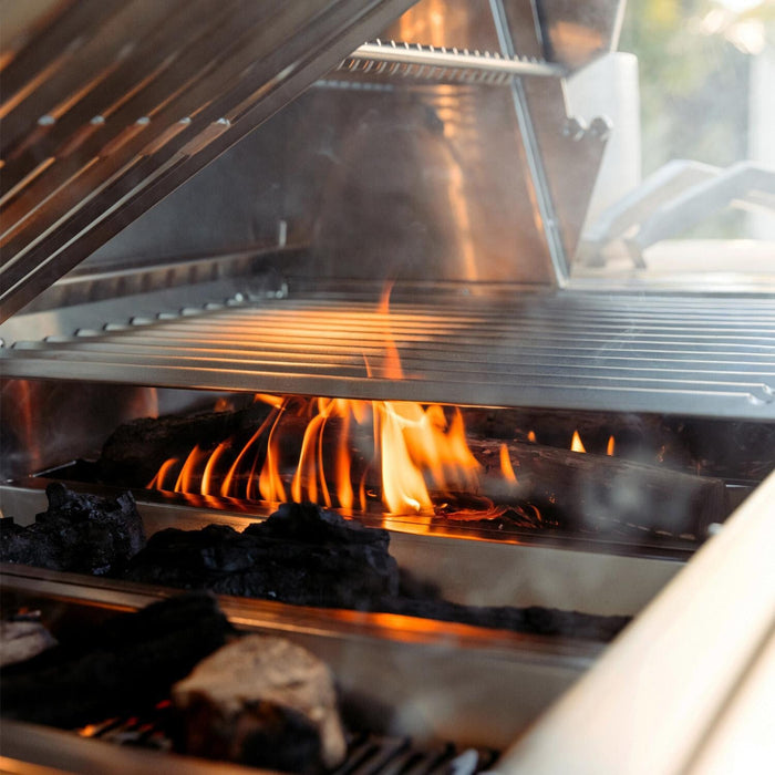 American Made Grills Encore 54-Inch Hybrid Grill with open flame and charcoal grilling in action